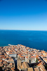 Fototapeta premium Aerial view of the coastal town of Cefalu in Sicily, Italy, showcasing its dense urban landscape and the vast Mediterranean Sea