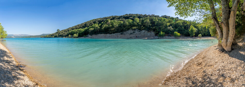 Sainte-Croix-du-Verdon, France - 07 05 2026: Panoramic view of the Lake Sainte-Croix, beach, hills and forests in sunny blue sky