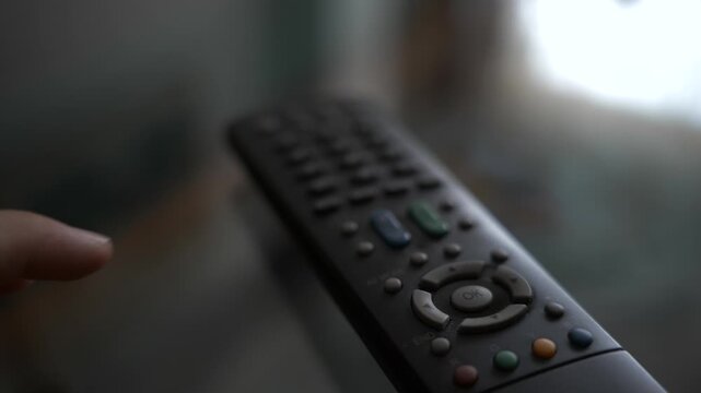 A person pressing the volume button on a remote control