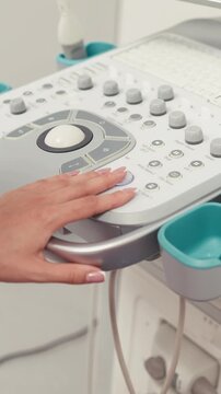 Woman's hand operating ultrasound equipment during a medical examination. Concept medical diagnostics, ultrasound technology, healthcare, clinical workflow, modern medicine.