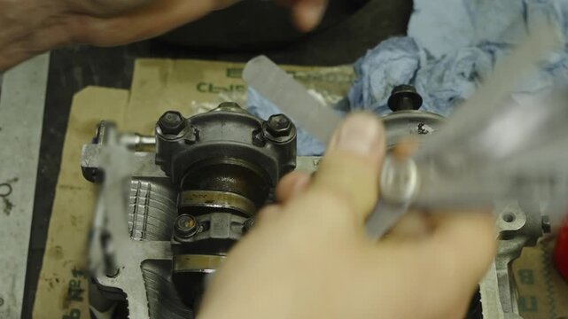 Mechanic holding a feeler gauge set to measure engine clearances.