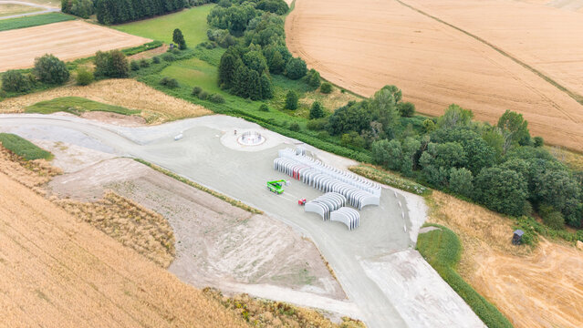 Construction site, preparation for building wind turbine farm, concrete tower section, foundation area, rows of curved segments, gravel ground in forest, Germany