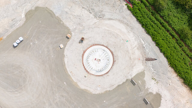 Construction site, preparation for building wind turbine farm, concrete tower section, foundation area, rows of curved segments, gravel ground in forest, Germany