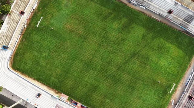 Sports stadium and athletic field aerial view empty green grass pitch with running track and spectator stands drone shot