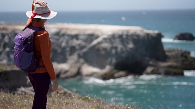 Mature woman hikes along the scenic Point Arena Coastal Trail near Mendocino. She smiles while taking in the Pacific Ocean views.
