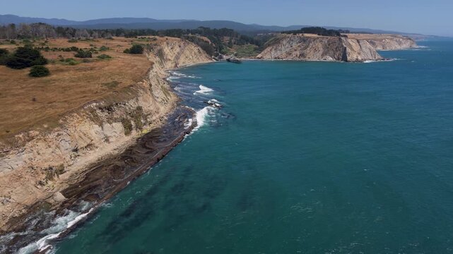 View aerial shots of Point Arena Fishing Pier near lighthouse and cliffs on the northern California coast south of Mendocino.