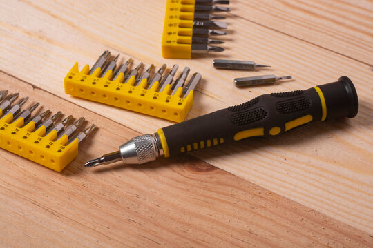 Screwdriver with Interchangeable Bits on Wooden Surface