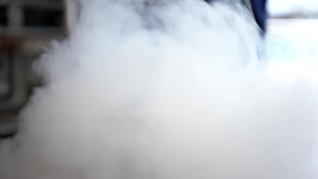 Thick white vapor clouds emerge from a container holding liquid nitrogen in an industrial setting.