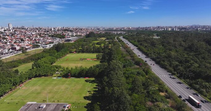 4K aerial drone footage of a professional football training center beside Parque Ecol&oacute;gico do Tiet&ecirc; in S&atilde;o Paulo, Brazil, on a sunny day.