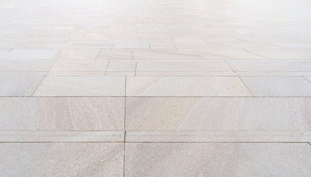 Light-colored stone paving with rectangular tiles extending into the distance, showing texture and grout lines.