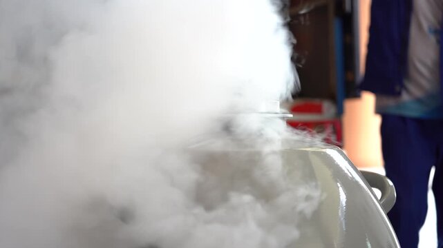 Close-up of thick white vapor rising from a container of liquid nitrogen in an industrial setting.