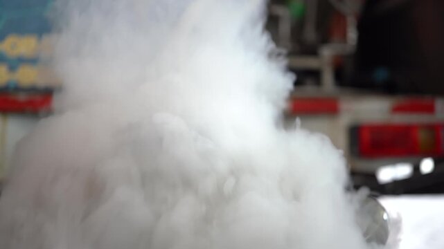 Close-up of an industrial metal container emitting thick cold vapor smoke in a factory setting.