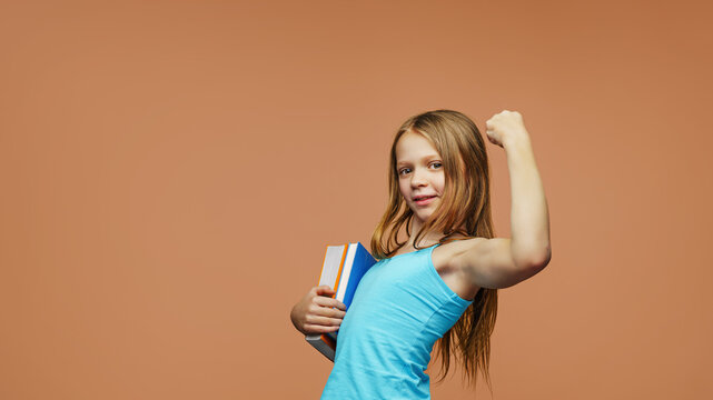 A happy schoolgirl with a books stands on an isolated background. Back to school and joy of learning concept.