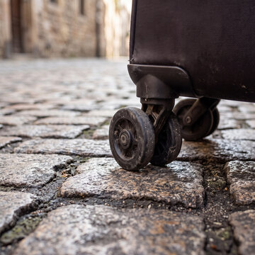 Suitcase Wheels Rolling Across Old Cobblestone Street Close-Up