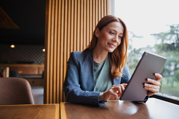 Attractive female professional working on a tablet computer while sitting in a coffee shop © Novak