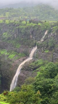 Ahupe Village waterfall amid lush monsoon greenery, Maharashtra, India.