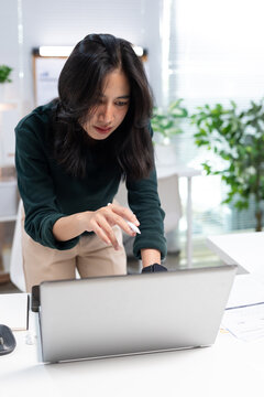 Young businesswoman working on laptop in modern office. Professional using computer for project planning, business management, and workplace productivity.