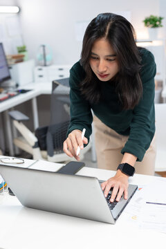 Young businesswoman working on laptop in modern office. Professional using computer for project planning, business management, and workplace productivity.
