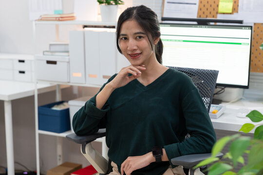 Portrait of smiling young Asian woman sitting at desk In the office
