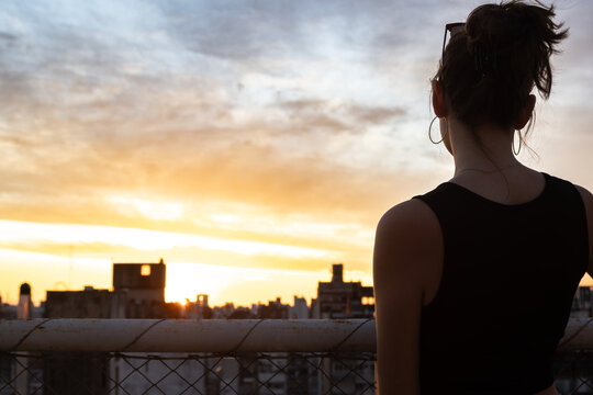 Teenager standing on a rooftop watching the golden hour sunset