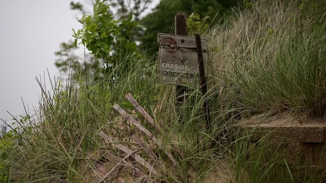 4K video of an erosion warning and keep out sign among protected beach dunes and native grasses