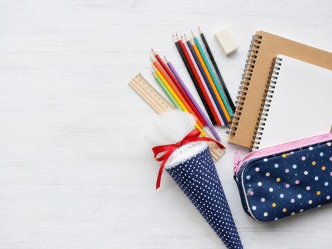 Schulmaterial zur Einschulung in Deutschland: Schult&uuml;te, M&auml;ppchen, Hefte, Lineal, Radierer und bunte Stifte liegen auf hellem Holz mit gro&szlig;z&uuml;gigem Freiraum f&uuml;r Text.