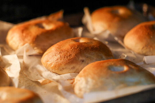 Close-up of homemade bagels baking in an oven, highlighting golden crusts, artisan baking, fresh bread, and handcrafted bakery-style food.