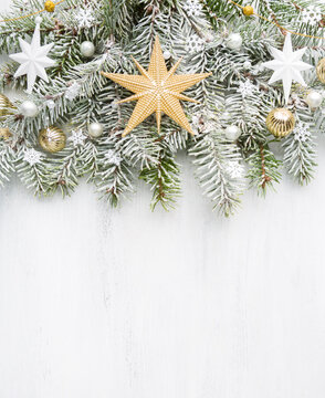 Spruce branch covered with snow and decorated with Christmas ornaments on old white wooden shabby board with empty space for text. Christmas and New Year background with holiday decorations. Flat lay