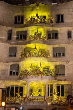 Barcelona, Spain &ndash; January 2, 2026: Festive golden star decorations illuminate the iconic stone balconies of Gaud&iacute;'s Casa Mil&agrave; at night.
