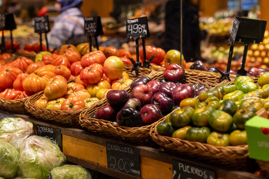 Large, vibrant beefsteak tomatoes are perfectly arranged in wicker baskets at a local market stall.