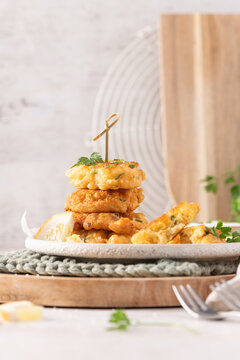 Delicious golden crispy cod fish fritters stacked on a rustic plate with fresh green parsley garnish and a lemon wedge for a perfect appetizer