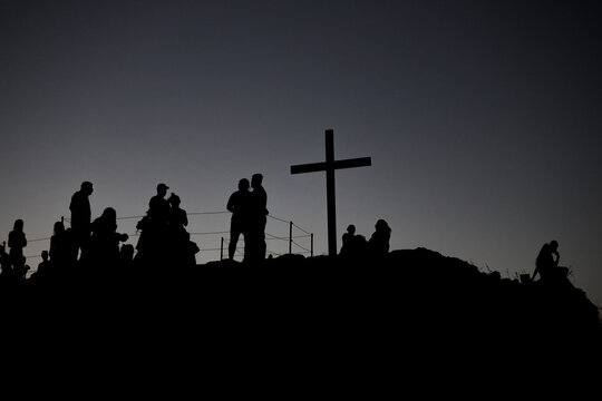 Silhouetted visitors gather beside a prominent cross on Areopagus Hill in Athens, Greece, the traditional site associated with the Apostle Paul's famous sermon.