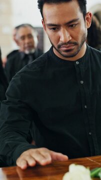 Man, mourning and rose at funeral with coffin, condolences and memorial service for deceased. Person, greeting and flower with casket at church for rip, final goodbye and burial for farewell ceremony