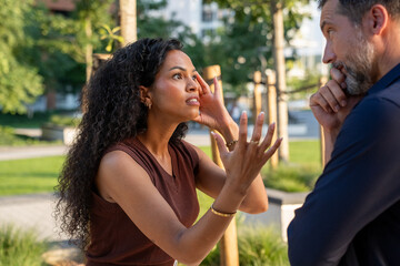 Fototapeta premium Frustrated woman arguing with uninterested man outdoors, relationship conflict and communication problems in urban environment