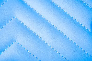 Obraz premium Elegant pastel blue quilted leatherette fabric texture background with distinct diagonal stitching design