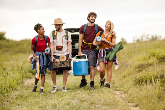 Group of Friends Carrying Camping Gear While Hiking on a Trail in the Countryside