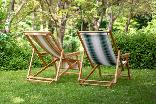 Two wooden deck chairs on lush green lawn summer relaxation vacation holiday rental agriturismo garden