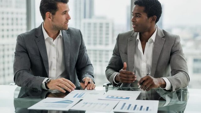 Medium shot of two business partners concentrating on financial charts during a coborrower structuring session emphasizing income blending for stronger loan approval.