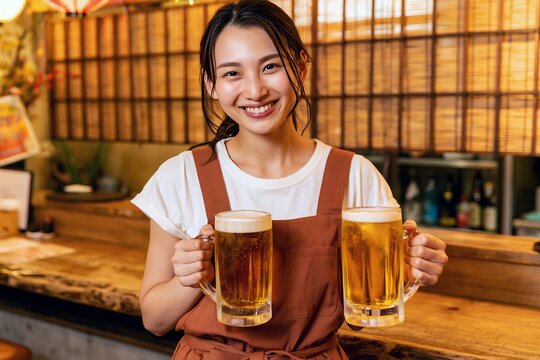 居酒屋のカウンターで笑顔の女性がビールジョッキを掲げる