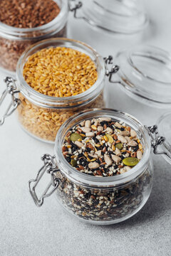Assorted seeds in glass jars on a light grey background