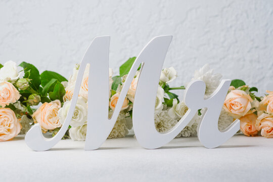 White wooden letters spelling Mr and Mrs with pastel roses and greenery