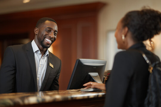 Smiling male receptionist assisting a guest at a hotel front desk