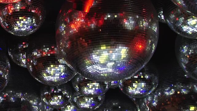 A dazzling birthday bash unfolds at a vibrant disco club. Numerous shimmering disco balls reflect an array of blue, purple, red, and orange lights, illuminating a festive night of fun.