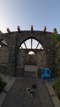 Walking into the open-air prayer area with stone arches at historic Masjid Bani Anif.