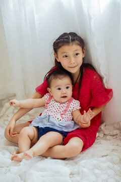 An Asian girl playing indoors with her baby.