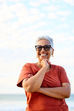 Smiling Woman Standing on the Beach at Sunset