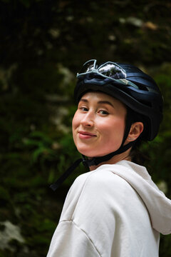 Smiling female cyclist wearing a helmet on a forest trail 