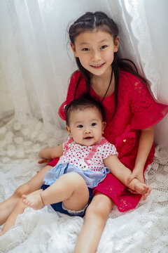 An Asian girl playing indoors with her baby.