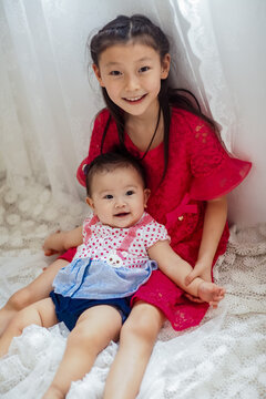 An Asian girl playing indoors with her baby.