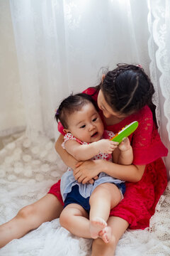 An Asian girl playing indoors with her baby.